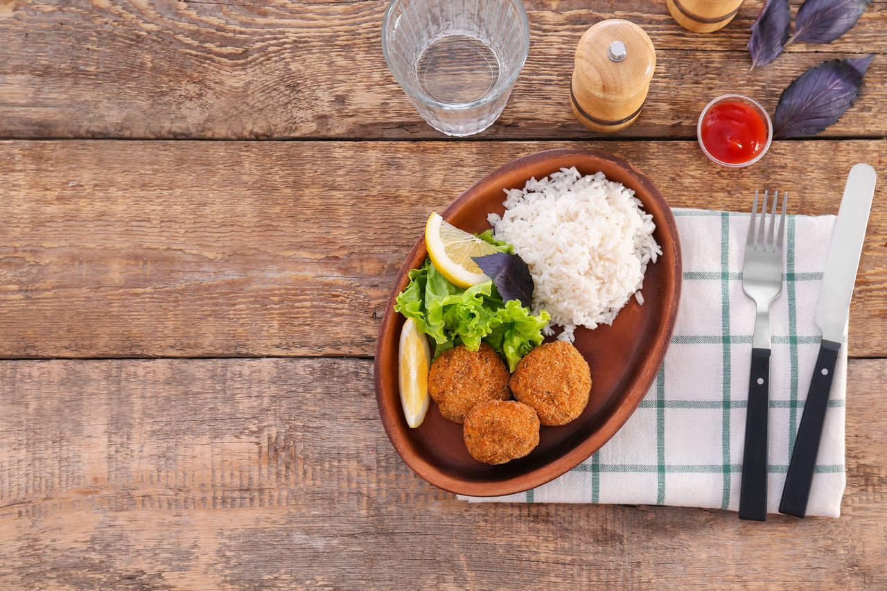 Gamelle de croquettes, pâtée ouverte et portion maison sur une table de cuisine.